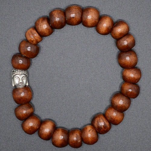 A beaded bracelet made of glossy medium-brown wooden beads with a small silver Buddha head charm, displayed on a neutral gray background.