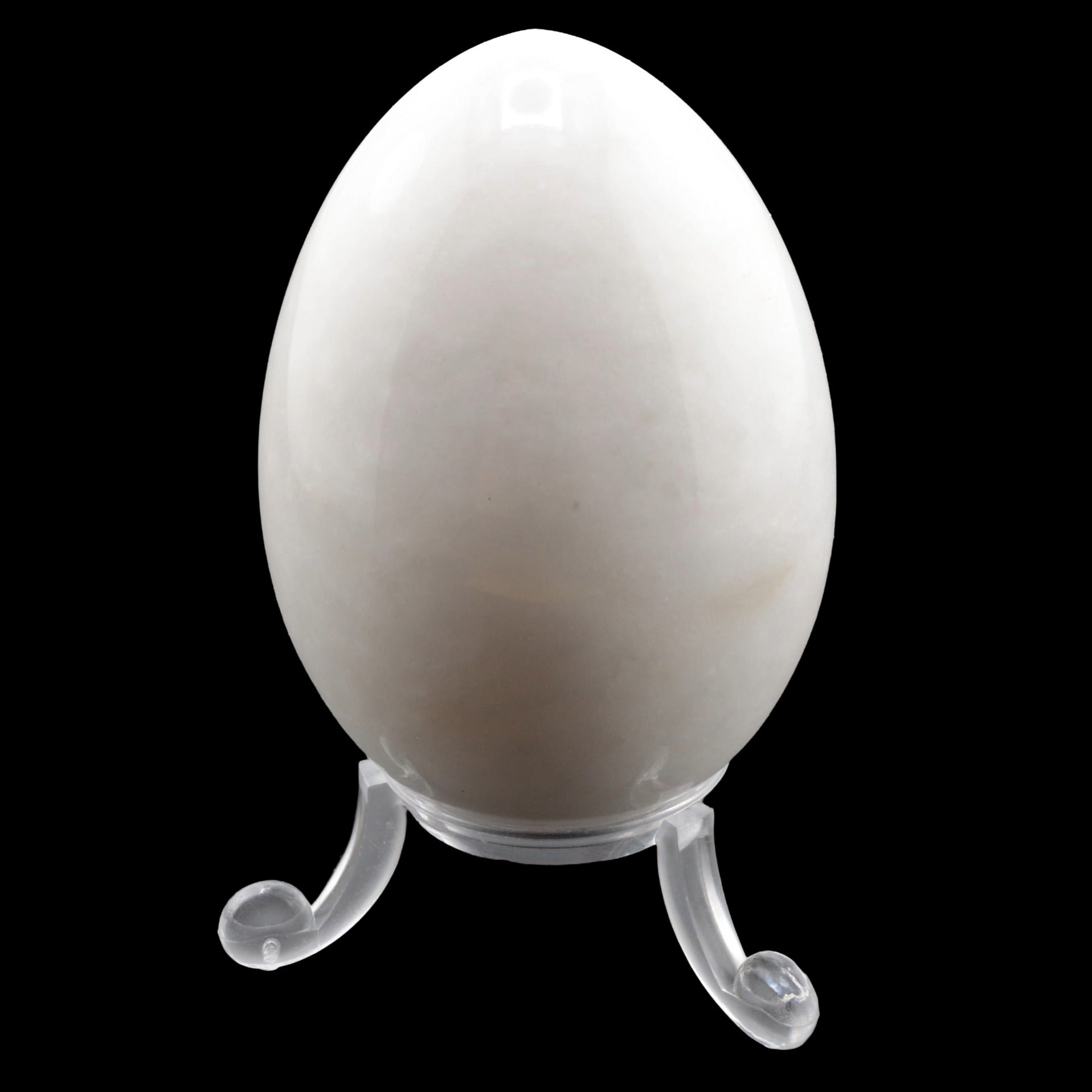 A smooth, polished white marble egg with grey veining displayed on a clear plastic stand against a solid black background.