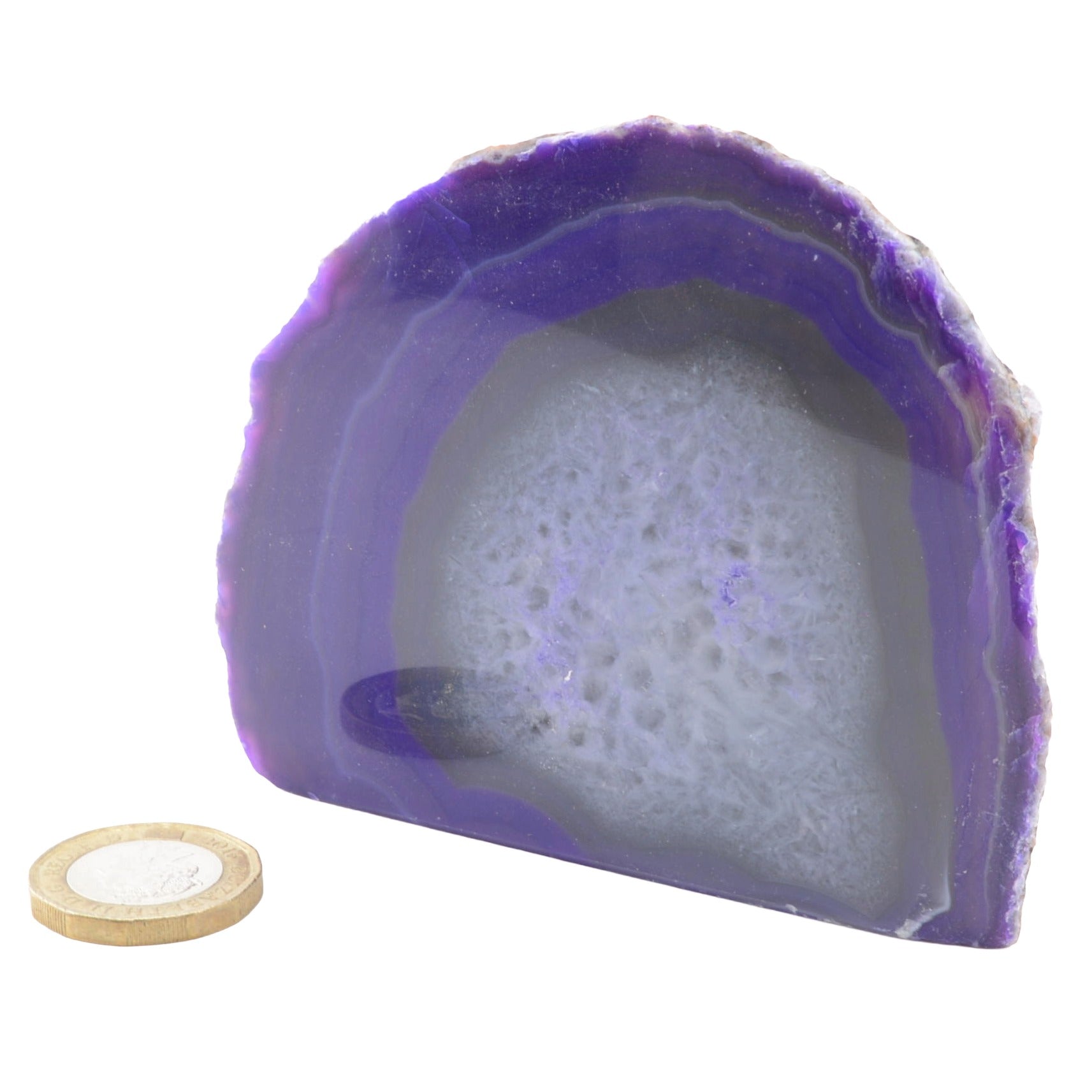 A polished purple agate geode with concentric banding and a white crystalline interior, shown on a white background with a small round wooden coin for scale.