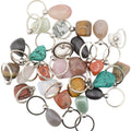A collection of polished tumbled gemstones in various colors and patterns, each attached to a silver split ring keyring, arranged on a plain white background.