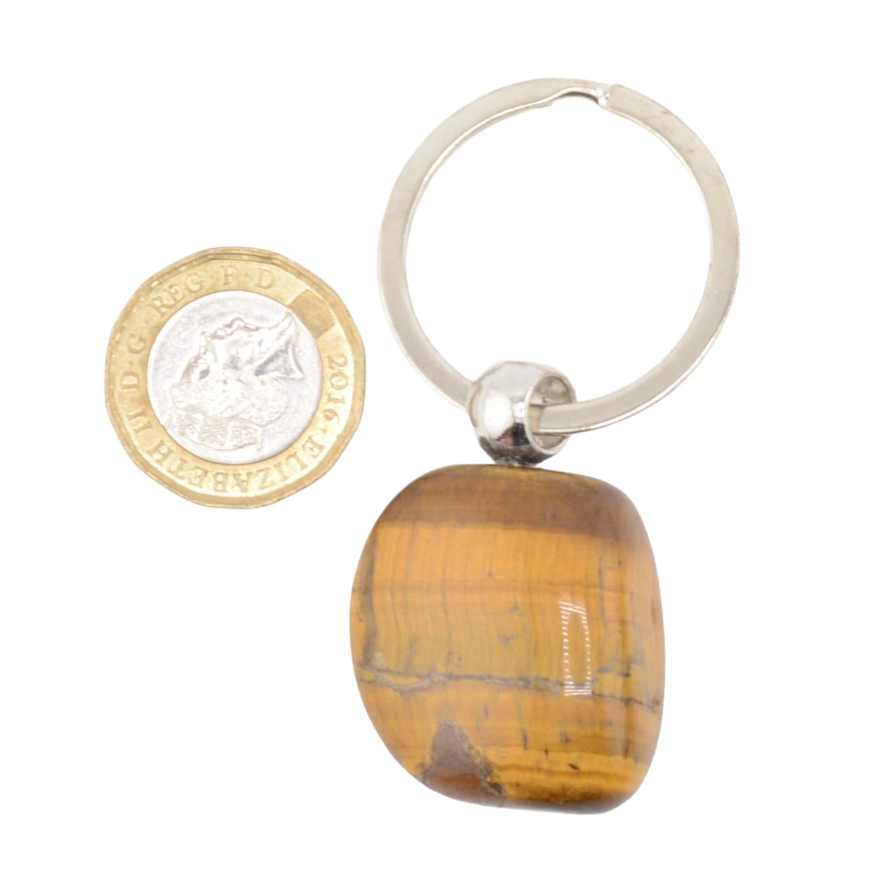 A polished tiger's eye stone keychain with a silver-colored metal split ring keyring, shown next to a British coin for scale on a white background.