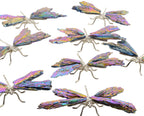 A set of dragonfly-shaped pieces with iridescent wings and silver-toned bodies and legs, arranged on a plain white background.