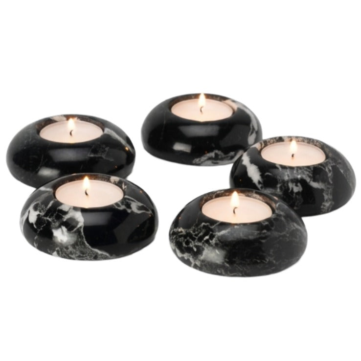 Four black marble tea light holders with white veining, each containing a lit tealight candle, arranged on a plain white background.