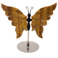 A decorative butterfly-shaped shelf piece with large warm brown Tigers Eye Gemstone wings, a black butterfly body, and a silver metal stand on a plain white background.