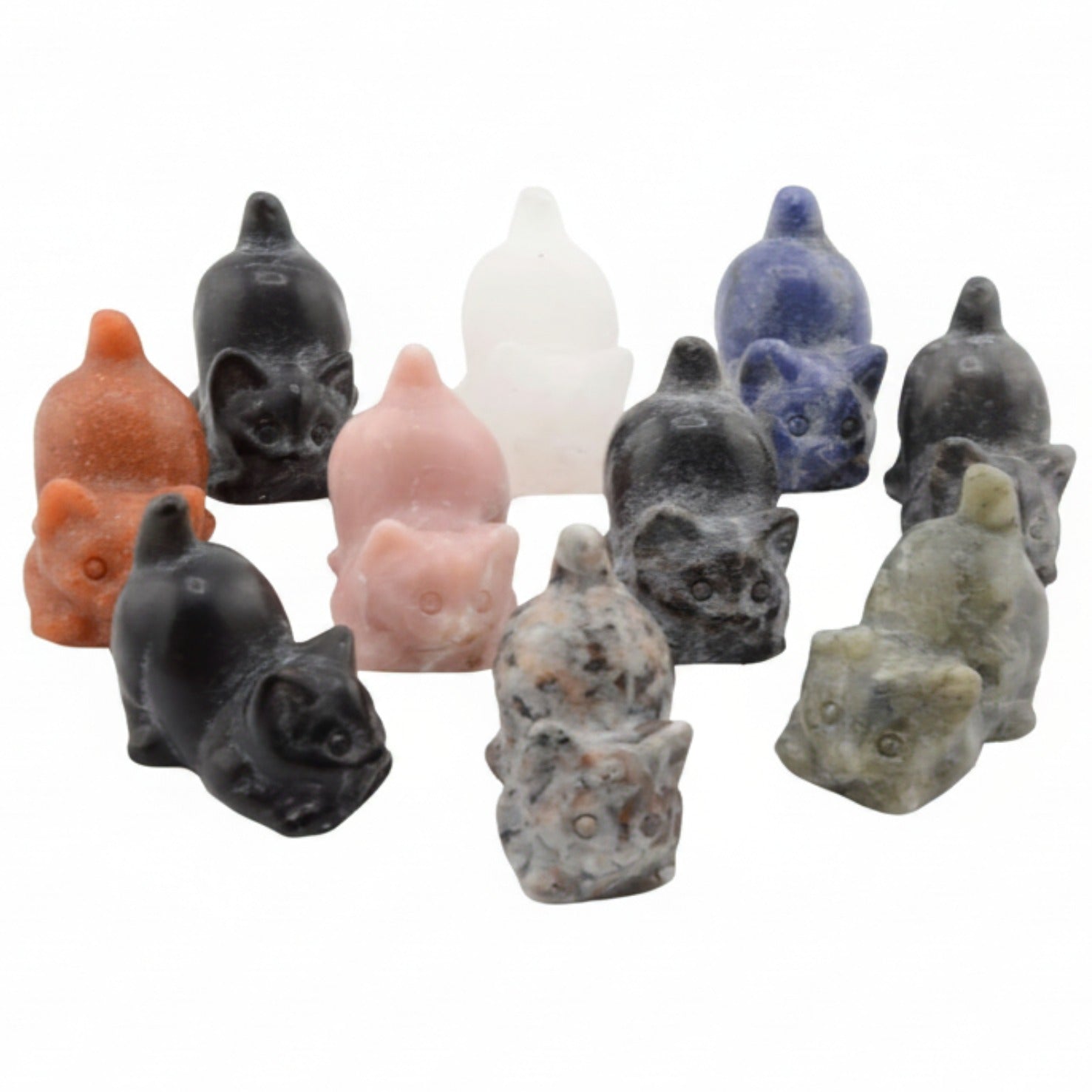 A group of small carved gemstone cat figurines in multiple natural stone colors, including black, pink, blue, orange, white, gray, and green, arranged on a plain white background.