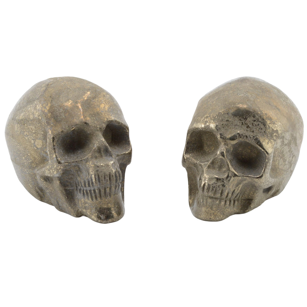 Two pyrite metallic skull-shaped decorative pieces shown side by side on a plain white background.