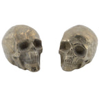 Two pyrite metallic skull-shaped decorative pieces shown side by side on a plain white background.