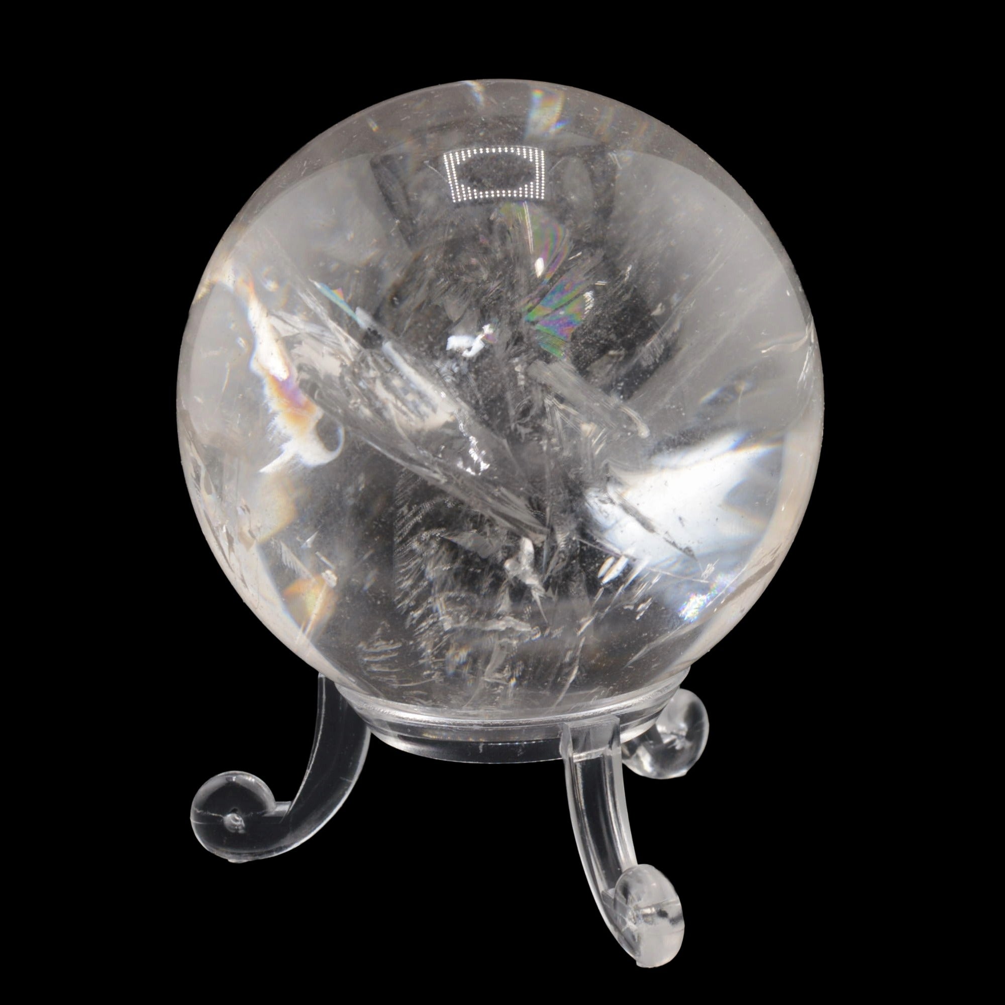 A clear quartz crystal sphere with visible internal needle-like formations, displayed on a small clear stand against a solid black background.