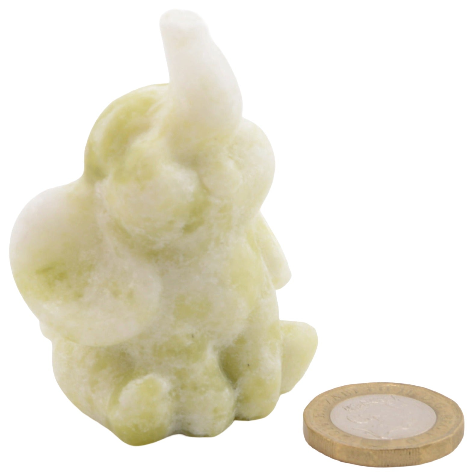 A 6cm carved elephant figurine in a pale yellow-green and white marbled serpentine gemstone, shown next to a round wooden coin for scale on a plain white background.