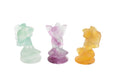 Three small fluorite crystal flower fairy carvings in green, purple, and yellow, arranged side by side on a plain white background.
