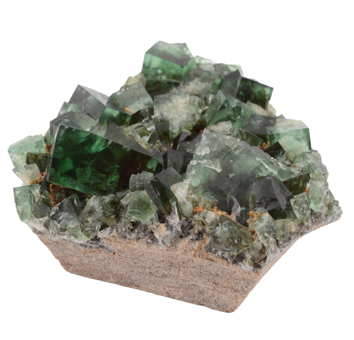 A natural fluorite crystal cluster with green and dark teal transparent cubes growing on a tan matrix, photographed against a plain white background.