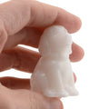 A small white dog figurine being held between fingers against a plain white background.