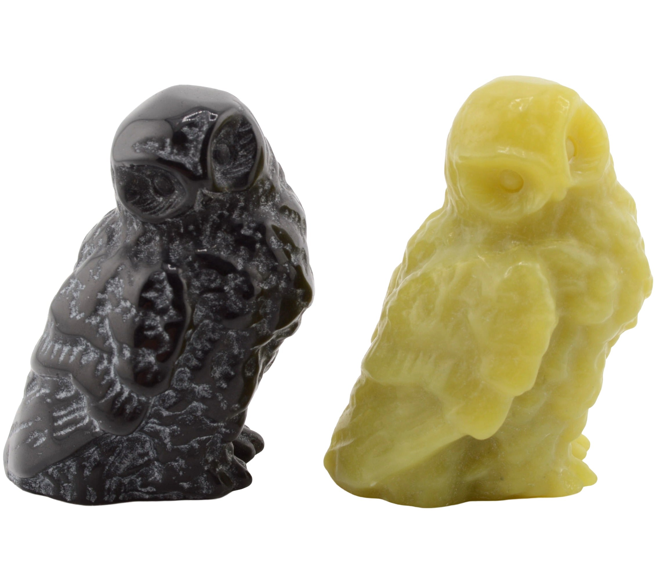 Two small carved owl figurines on a plain white background, one in black and one in green.