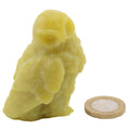 A small carved stone owl figurine in pale yellow, shown next to a coin for scale on a plain white background.
