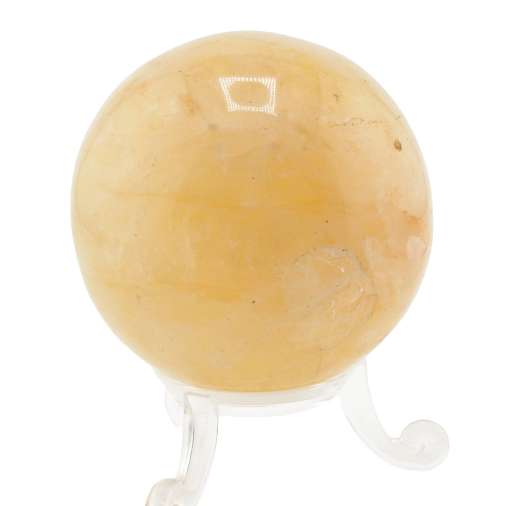 A polished golden healer quartz crystal sphere resting on a clear acrylic display stand, isolated on a white background.