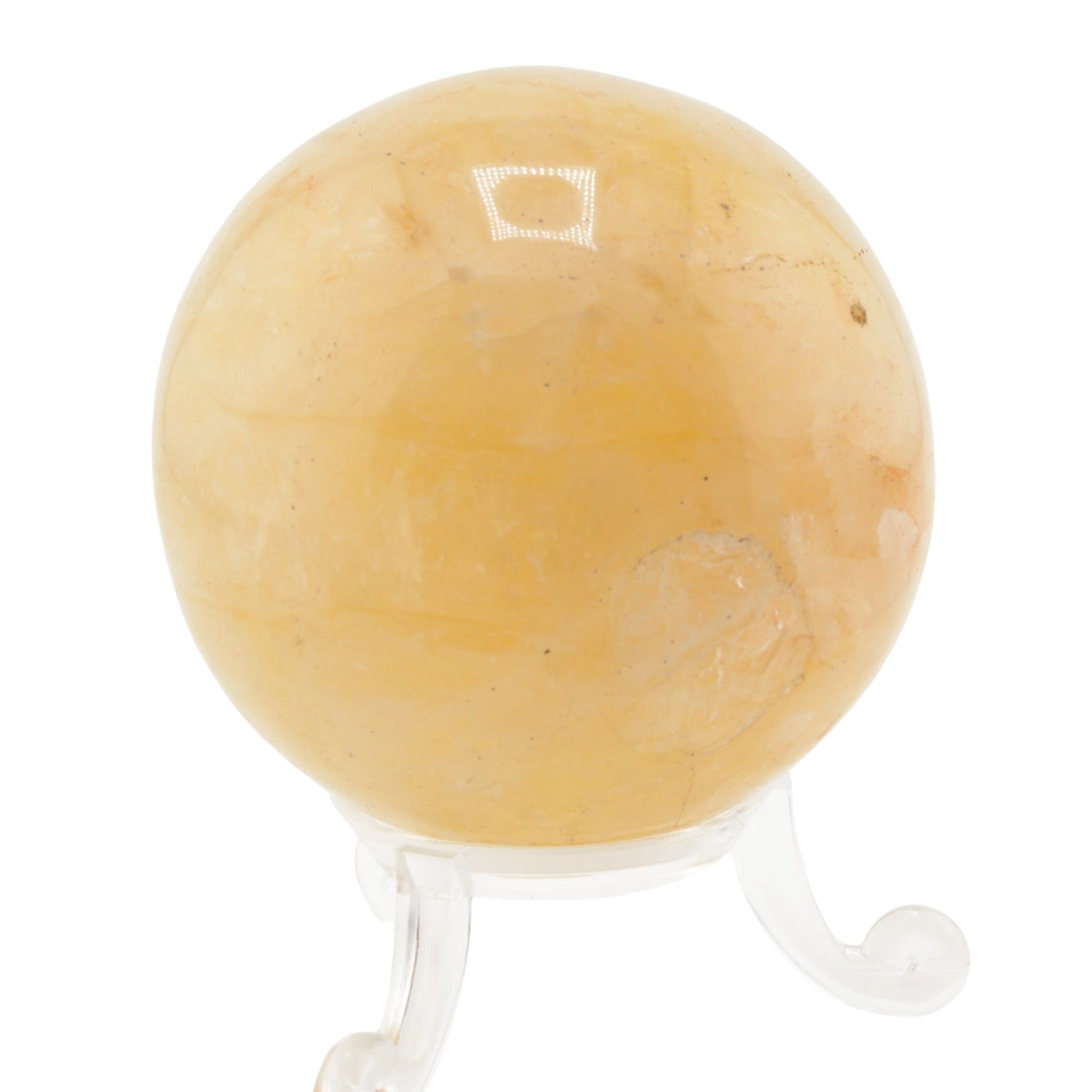 A polished golden healer quartz crystal sphere resting on a clear acrylic display stand, isolated on a white background.