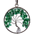 A circular tree of life pendant featuring green aventurine chip stones for the leaves, a silver wire trunk and branches, and a dark metal outer ring on a white background.