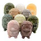 A set of small hedgehog figurines in multiple pastel and earthy colors, including green, pink, brown, beige, gray, white, and orange, arranged together on a plain white background.