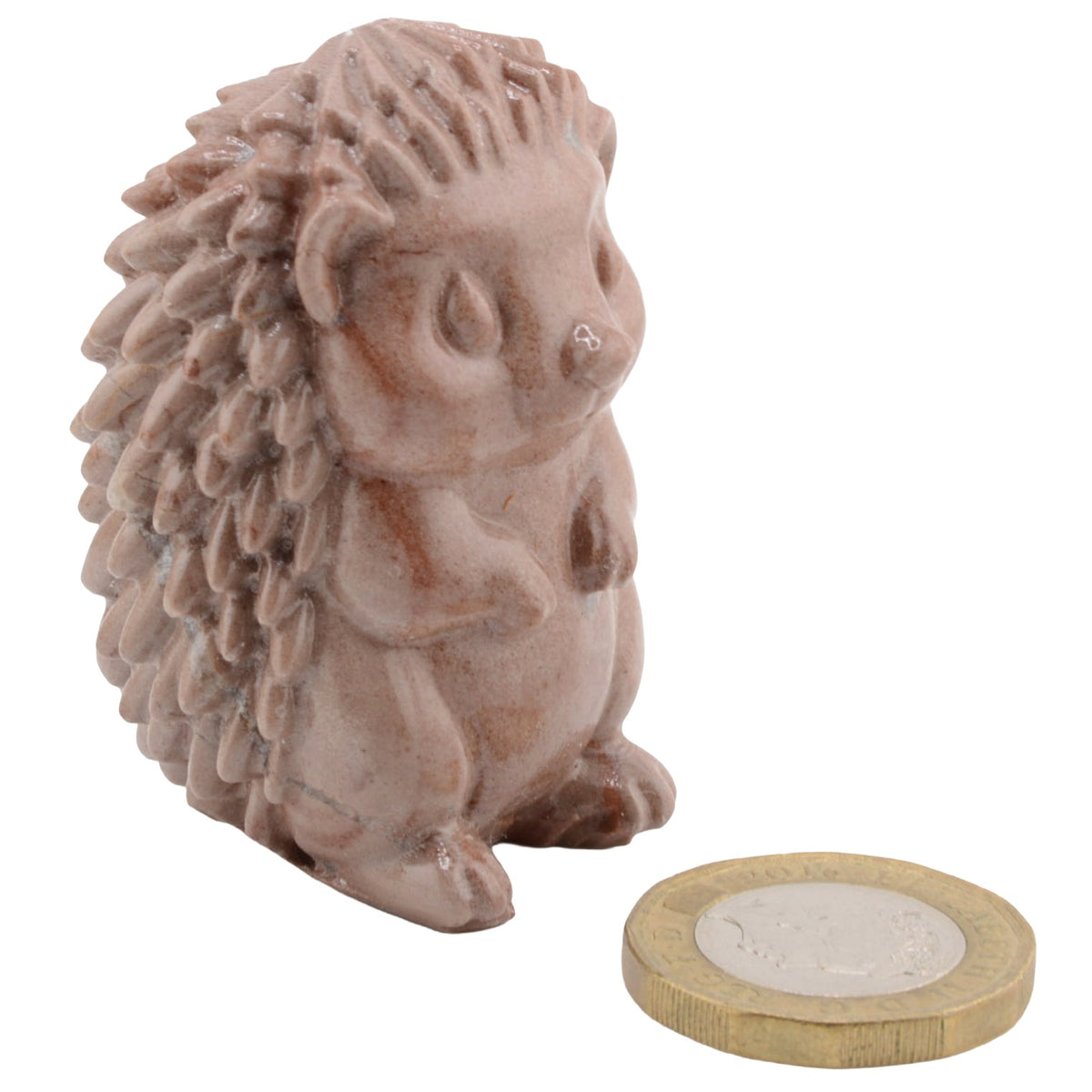 A small hedgehog figurine in a dusty pinkish-brown glaze, shown next to a coin for scale on a plain white background.