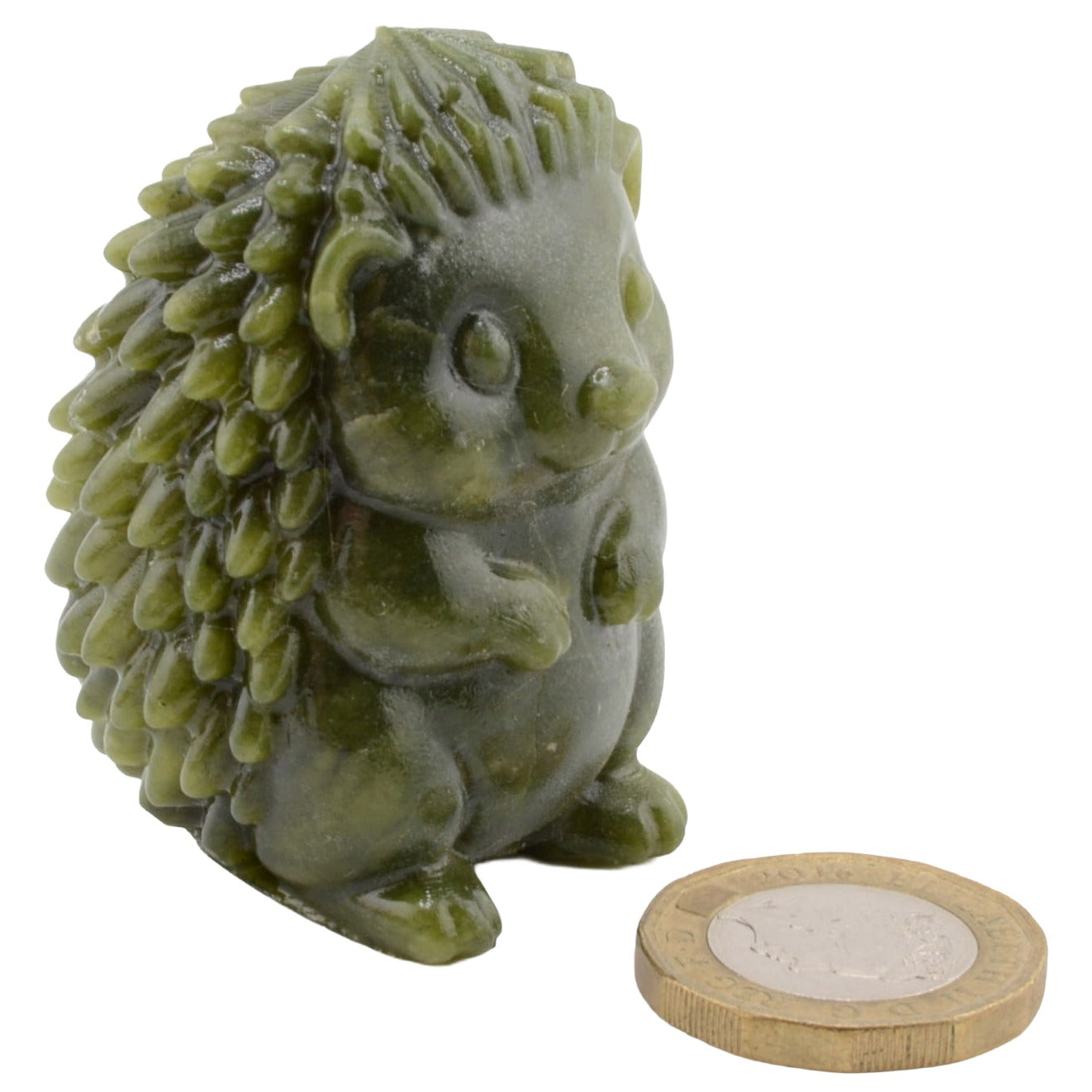A small green hedgehog figurine shown on a plain white background, with a UK one-penny coin placed in front for scale.