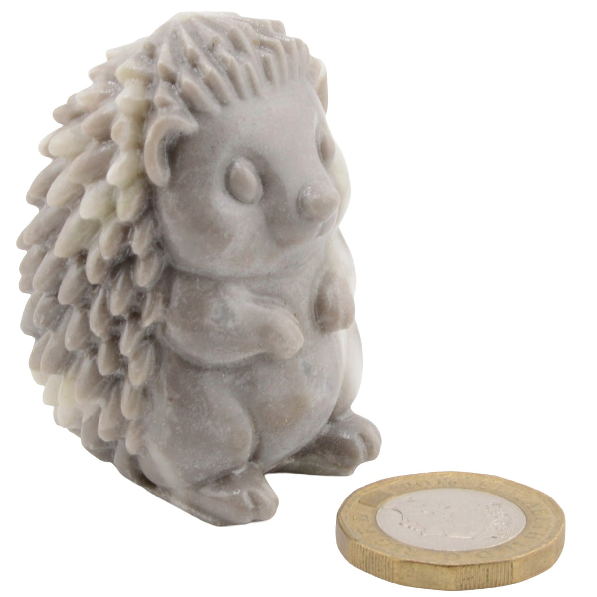 A small gray stone hedgehog figurine shown on a white background next to a UK two-penny coin for scale.