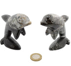Two small polished stone dolphin figurines shown side by side on a white background, with a coin placed below for scale.