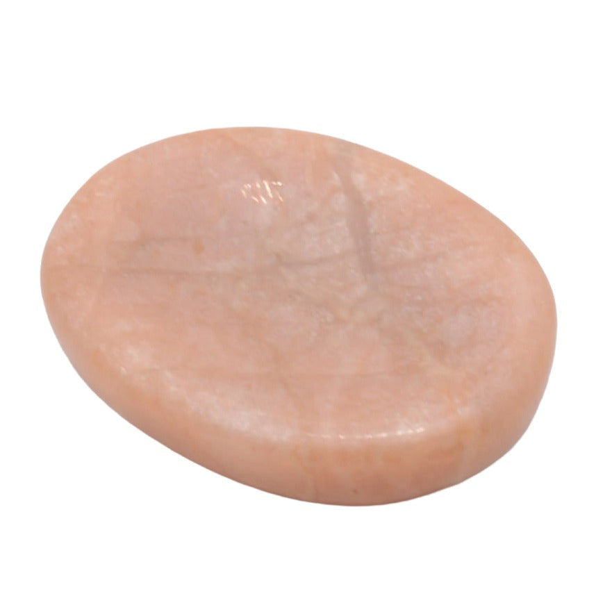 A smooth, polished peach-colored stone slab with natural mineral veining, photographed on a solid white background.