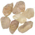 Seven polished tumbled natural citrine gemstones in pale cream, beige, and translucent yellow tones, arranged on a plain white background.