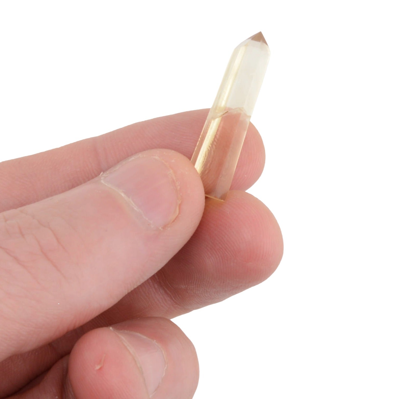 A hand holding a small,  natural citrine polished point crystal against a plain white background.