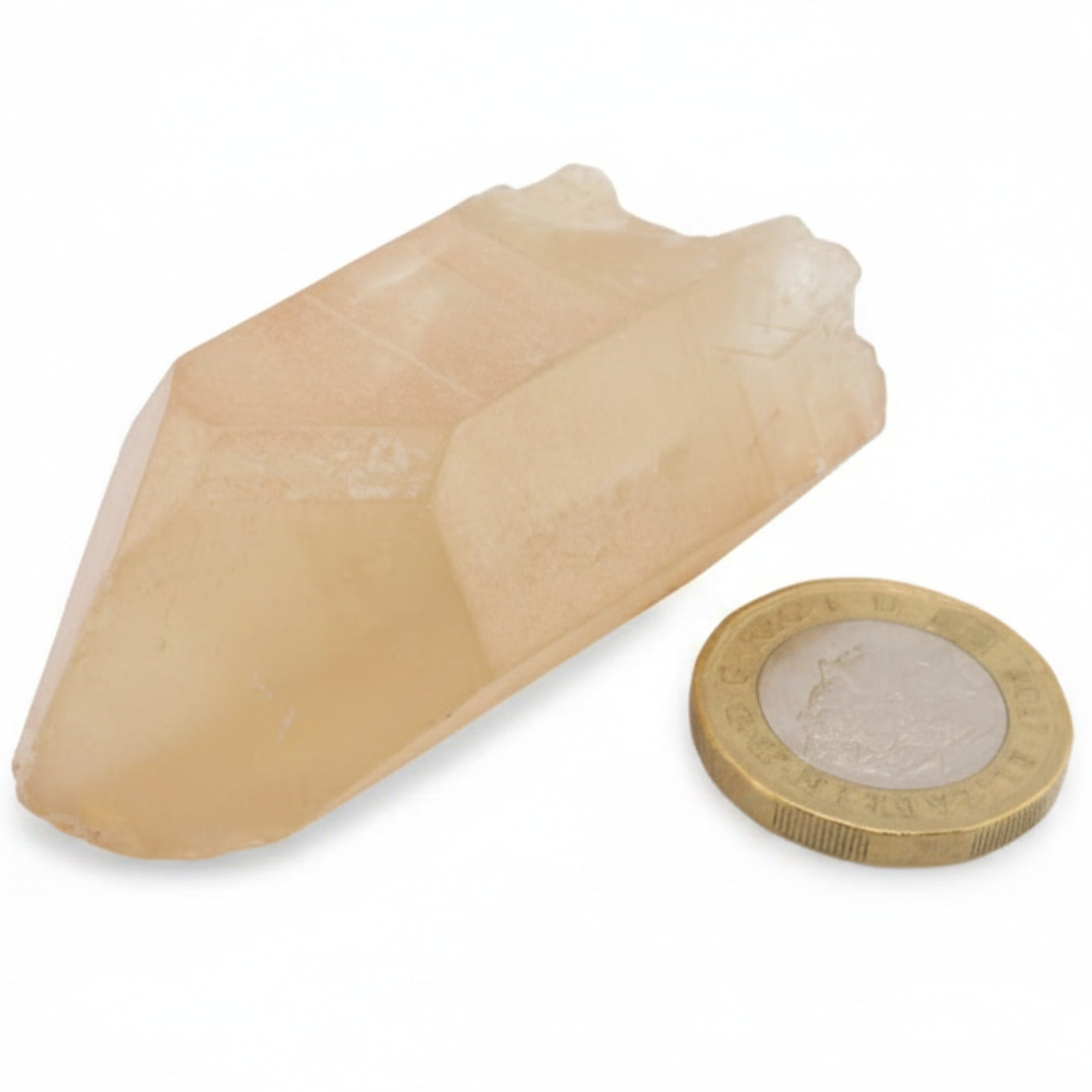 A natural citrine crystal rough point  next  to a UK pound coin for scale, on a clean white background.
