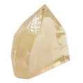 A faceted natural citrine crystal point, wighing 100g, in a pale yellow or citrine color, shown on a plain white background.