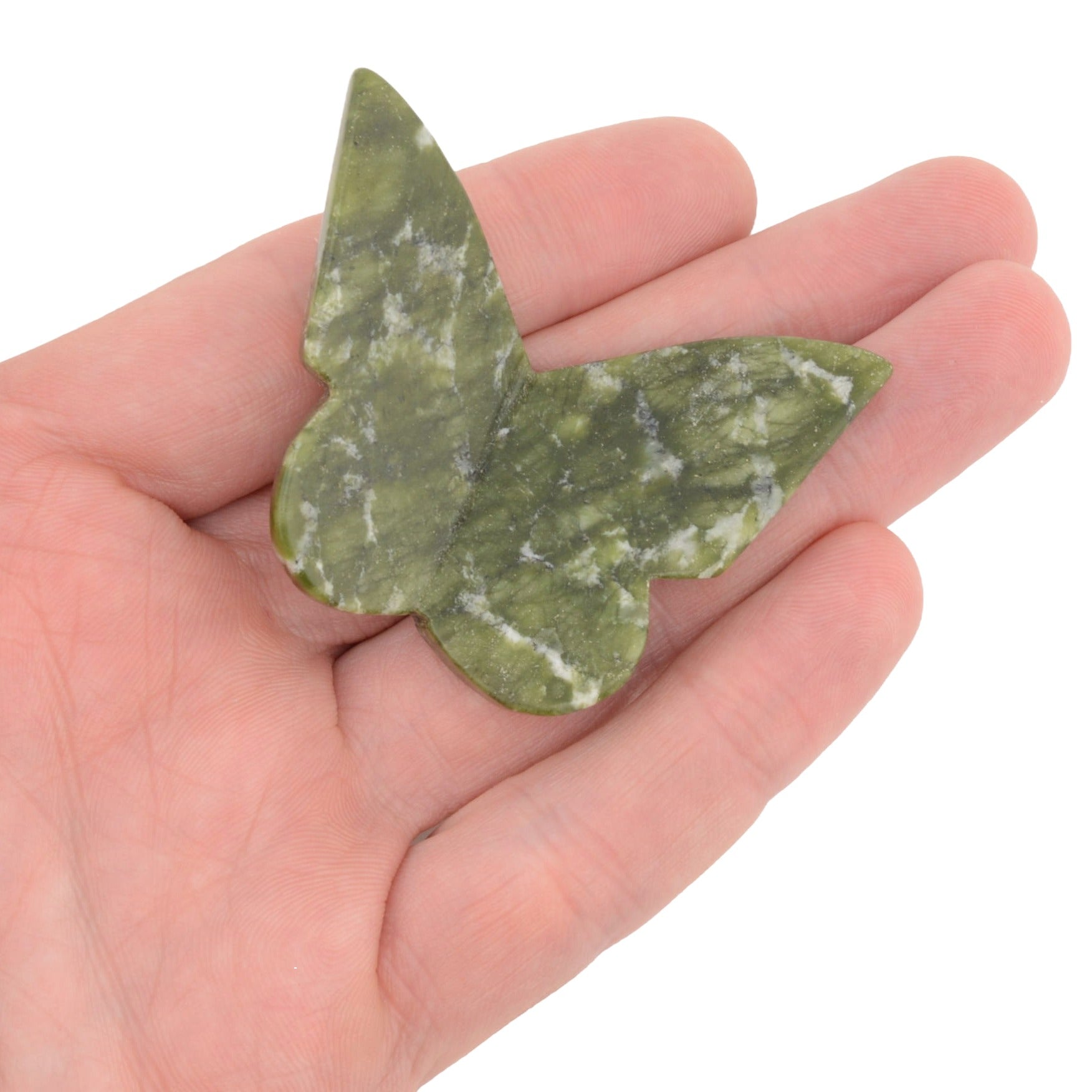 A green marbled nephrite jade gemstone butterfly carving resting on an open hand against a plain white background.