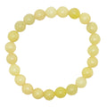 A beaded stretch bracelet made of polished olive jade beads in a pale yellow / green color, displayed on a solid white background.