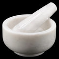 A white marble mortar and pestle set against a solid black background.