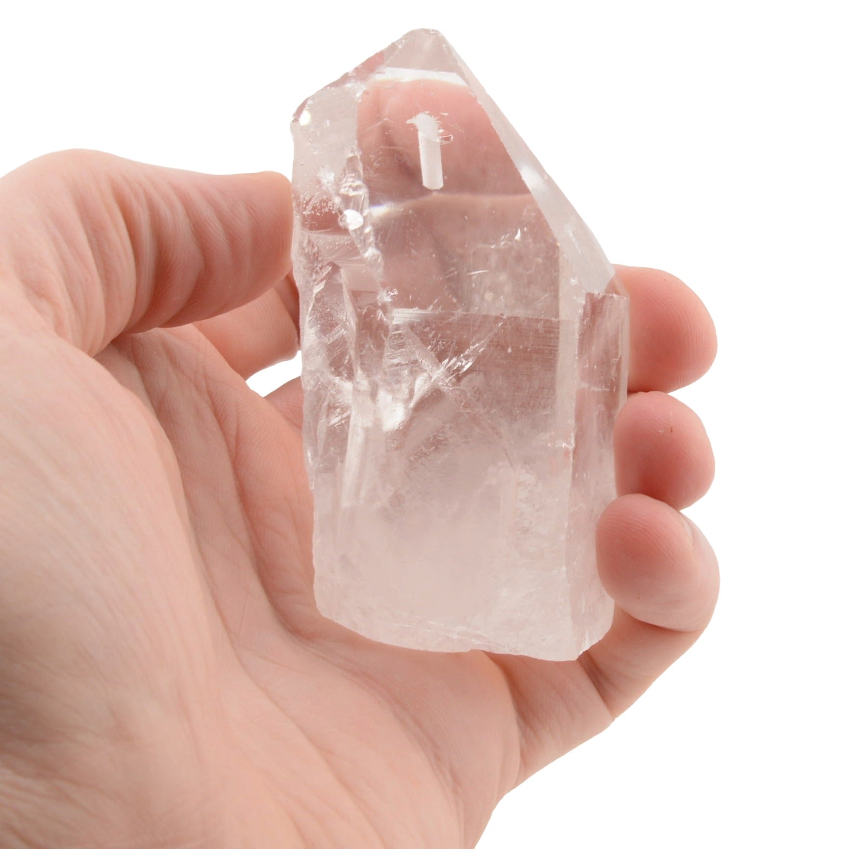 A hand holding a raw, pointed clear quartz crystal incense holder against a solid white background.