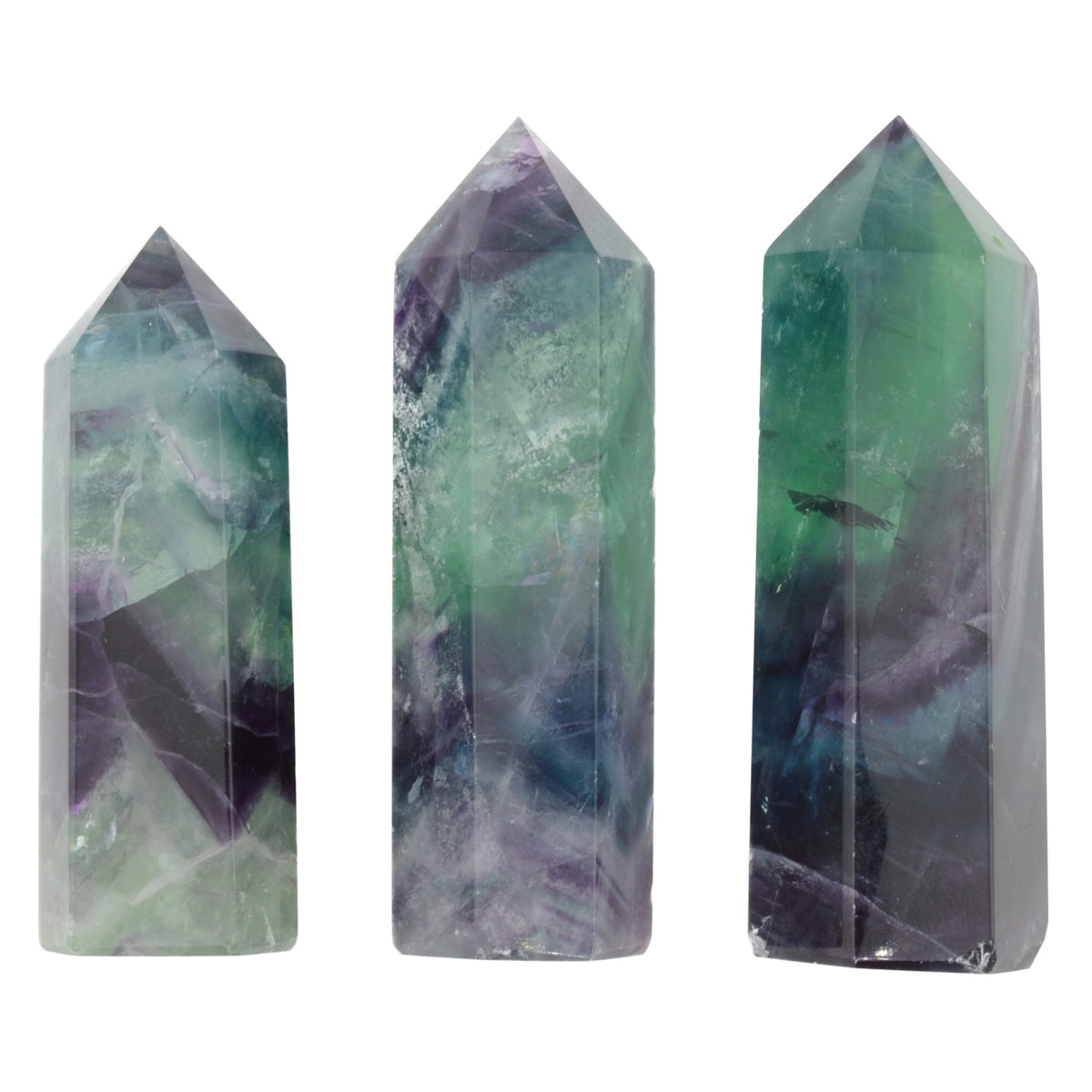 Three faceted crystal point towers in natural fluorite, featuring marbled patterns of green, purple, and gray, displayed against a solid white background.