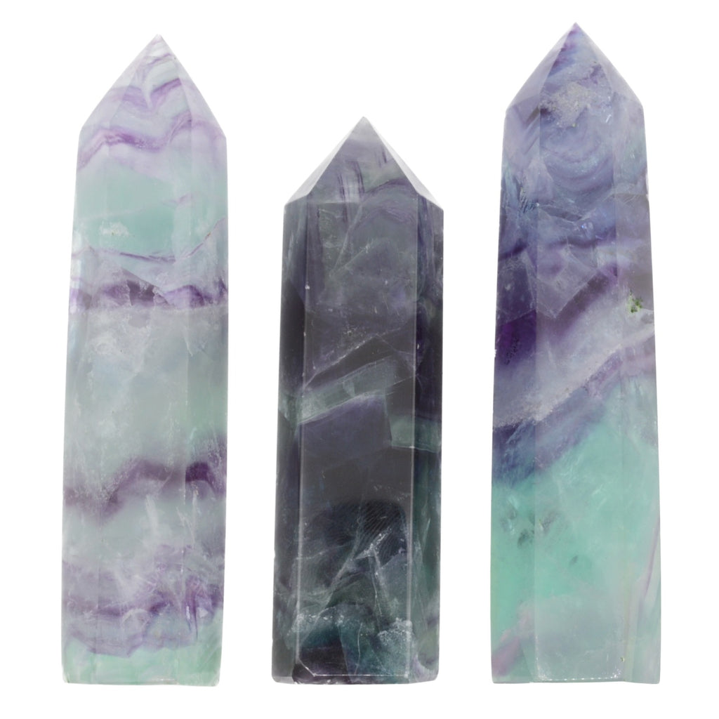 Three polished fluorite crystal points of varying heights, featuring natural marbled patterns in purple, mint green, and dark gray, set against a plain white background.