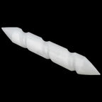 A selenite wand cylindrical tool with pointed ends, shown diagonally against a solid black background.