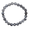A beaded stretch bracelet made of snowflake obsidian 8mm polished round beads with a black and white mottled, stone-like pattern, shown on a plain white background.
