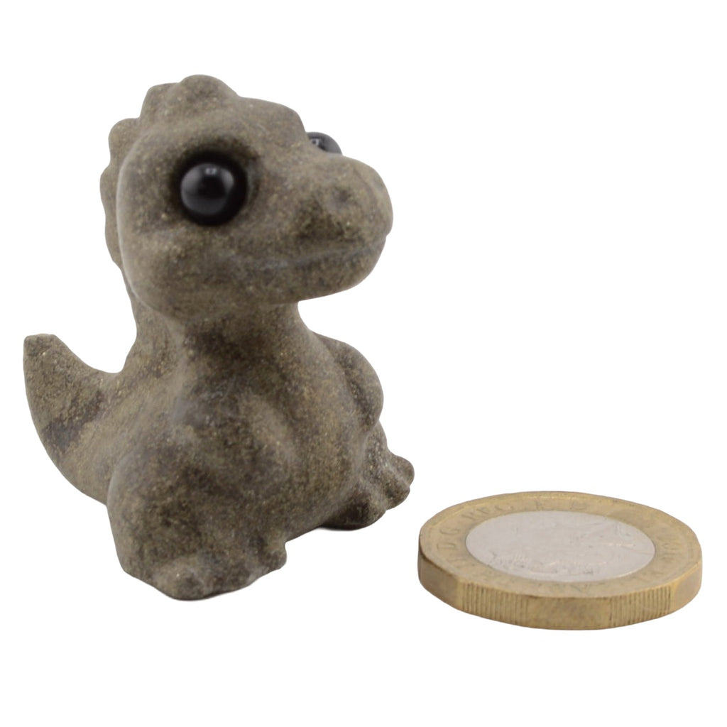 A small dinosaur T-Rex figurine made from natural gemstone with large black eyes, shown next to a coin for scale on a plain white background.