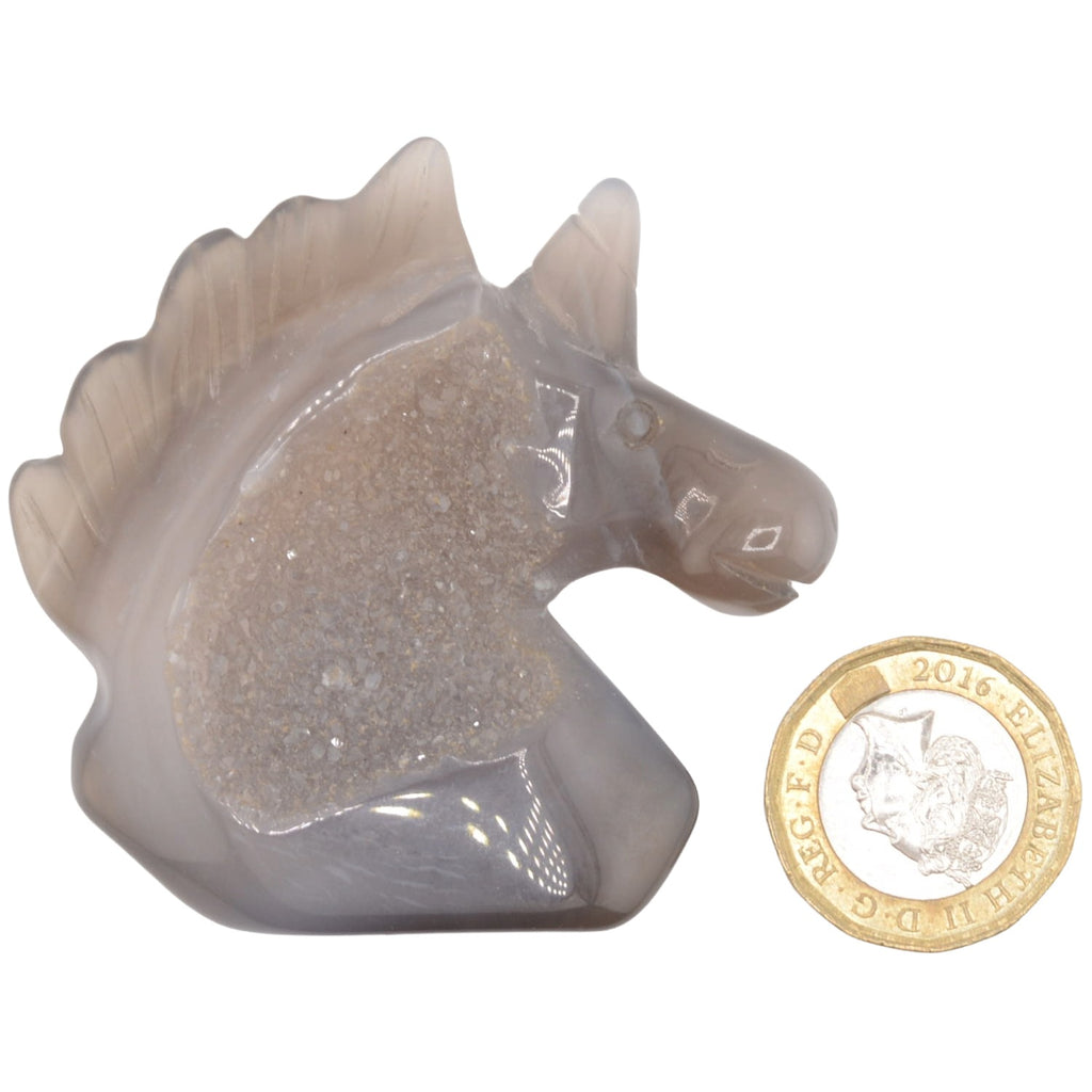 Unicorn Carving made from druzy agate. Pictured next to a pound coin for scale on a white background